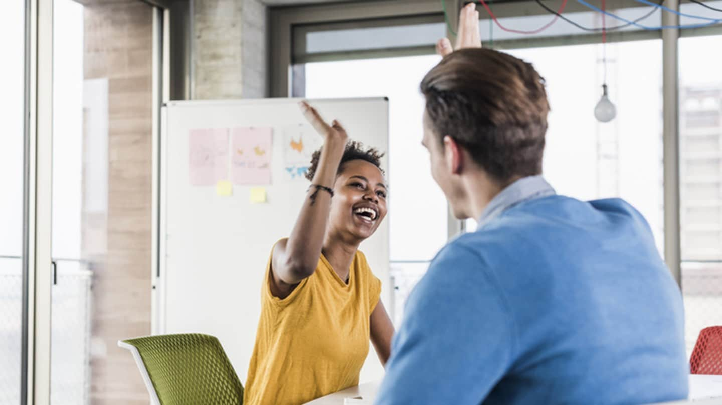 Two co-workers high-fiving each other in an open office area